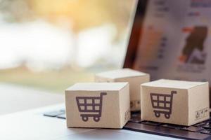 Online einkaufen. Karton mit einem Warenkorb-Logo auf der Laptop-Tastatur. Einkaufsservice im Online-Web. bietet Lieferung nach Hause an