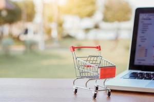 Online einkaufen. Einkaufswagen oder Trolley auf der Laptop-Tastatur. Einkaufsservice im Online-Web. bietet Lieferung nach Hause an foto