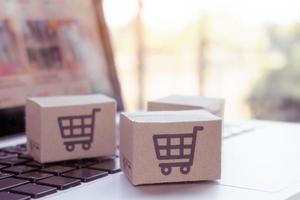 Online Einkaufen. Karton mit einem Warenkorb-Logo auf der Laptop-Tastatur. Einkaufsservice im Online-Web. bietet Lieferung nach Hause an foto