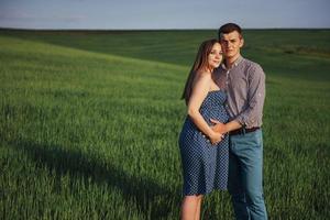 glückliche familie, die in einem feld des grünen weizens umarmt foto