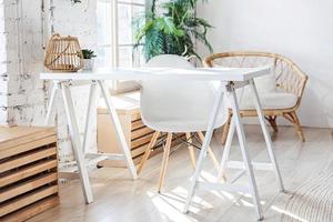 stilvolles loft modernes home-office-interieur. Geräumiges Design-Apartment mit hellen Wänden, großen Fenstern und Schreibtisch. saubere moderne dekoration mit eleganten möbeln im minimalistischen skandinavischen stil. foto