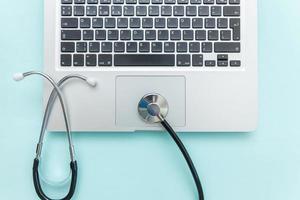 Stethoskop-Tastatur-Laptop-Computer isoliert auf blauem Hintergrund. moderne medizinische informationstechnologie und software bringen konzept voran. Diagnose und Reparatur von Computern und Geräten foto
