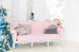 Schönes, klassisches, sauberes Luxus-Interieur-Wohnzimmer in weißer Farbe mit rosafarbener Sofa-Blumenkomposition. Helles, modernes, stilvolles Wohnzimmer mit Möbeln im klassischen minimalistischen Stil. foto