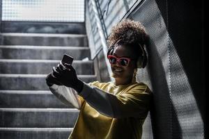 fröhliche hipster-frau, die selfie auf der treppe macht