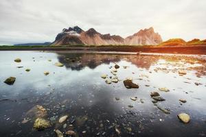 Erstaunliche Berge, die sich bei Sonnenuntergang im Wasser spiegeln. stoksnes, ic foto