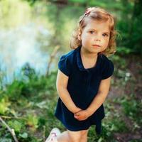 süßes kleines blondes mädchen ist vor dem hintergrund von wasser und g foto