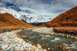 schneebedeckte Berge und lauter Gebirgsfluss. Georgien, Swanetien foto