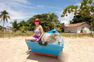 dame, die in einem alten hölzernen fischerboot sitzt, amüsiert sich am strand in corumbau, bahia, brasilien foto