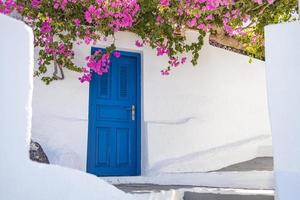 fantastischer reisehintergrund, stadtlandschaft von santorini. blaue Tür mit Treppen und Blumen, weiße Architektur unter blauem Himmel. idyllisches sommerferienferienkonzept. wunderbare Sommer-Luxus-Vibes foto
