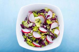 Detailansicht einer Schüssel mit grünem Salat auf blauem Hintergrund foto