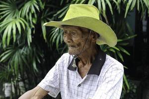 ein porträt eines indonesischen alten bauern trägt einen gelben hut mit einem alten fahrrad foto