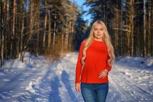 schöne glückliche blonde Frau im roten Pullover im Winterwald foto