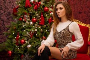 Porträt einer schönen jungen Frau auf dem Hintergrund eines Weihnachtsbaums foto