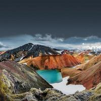 Landschaftsblick auf bunte regenbogenfarbene vulkanische Landmannalaugar-Berge und den berühmten Laugavegur-Wanderweg, mit dramatischem Himmel und Schnee in Island, Sommer foto