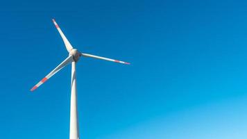 Banner mit einer einsamen großen Windkraftanlage zur Erzeugung von elektrischer Energie als grüne, umweltfreundliche Energie am blauen türkisfarbenen tiefen Himmel und Kopienraumhintergrund. konzept der nachhaltigen sauberen industrie und des lebens. foto