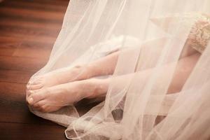 Brautvorbereitung am Morgen. Brautbeine im weißen Schleier auf Holzboden. foto
