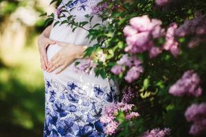 junge schwangere Frau gegen blühenden Baum im Frühjahr foto