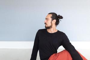 junger kaukasischer langhaariger weißer mann führt yoga in einem studio oder haus durch. foto