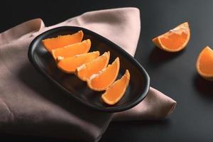 in Scheiben geschnittene orangefarbene Zitrusfrüchte auf schwarzem Hintergrund, inklusive Kopierbereich. foto