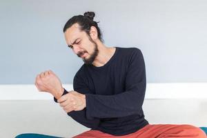 Der junge Sportler leidet während des Trainings oder beim Yoga unter Schmerzen an seinem Handgelenk foto