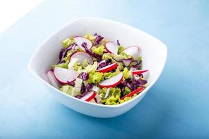 Detailansicht einer Schüssel mit grünem Salat auf blauem Hintergrund foto