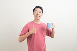 junger asiatischer mann, der kaffeetasse hält foto