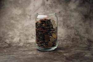 Glasflasche mit einer Flasche voller Münzen, um für zukünftige Geschäfte zu sparen. Sparidee. foto