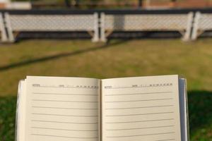 Nehmen Sie das linierte Notizbuch mit in den öffentlichen Garten, um Ideen, Werke oder Kunstwerke oder Erinnerungen zu schaffen. foto