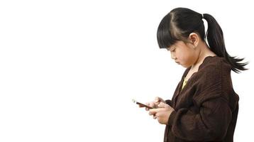 asiatisches Kind beobachtet das Telefon auf weißem Hintergrund, die Verwendung eines Mobiltelefons für eine lange Zeit tut ihren Augen weh und hat eine aggressive Atmosphäre. Konzept Gefahr für Kinderhandys Konzept. foto