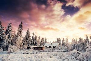 fantastischer Sonnenuntergang über schneebedeckten Bergen und Holzchalets foto