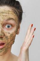 Hautpflege. Tag der Kosmetik. junges Mädchen im Homestyle, ihr Haar mit den Händen oben zusammengerafft. mit Öko-, Kräuter-, Naturmaske, grün im Gesicht. Vorderansicht.