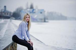 Porträt eines jungen süßen blonden Mädchens auf Bluse am nebligen Fluss im Hintergrund des Piers auf Wintereis. foto