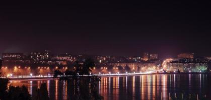 Panorama der nächtlichen Lichter der Stadt und Reflexionen auf dem See bei Ternopil, Ukraine, Europa.