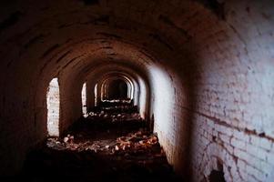 beängstigender Backsteinbogentunnel auf Dunkelheit und etwas Licht. foto
