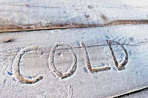 Kälte geschrieben auf einem hölzernen Hintergrund mit Frost foto