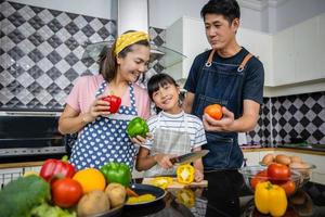 glückliche Familie hat Papa, Mama und ihre kleine Tochter, die zusammen in der Küche kochen foto