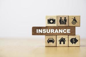 Symbol für Versicherung und Versicherung, einschließlich Familiengesundheitsimmobilienauto und Finanzdruckbildschirm auf Holzwürfelbock für Risikomanagementkonzept. foto
