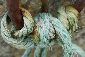 Blaues Seil, das an einen rostigen Eisenring gebunden ist foto