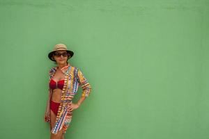 Frau mit Badebekleidung an eine grüne Wand gelehnt foto
