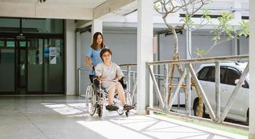 lächelnder Physiotherapeut, der sich um den glücklichen älteren Patienten im Rollstuhl kümmert foto