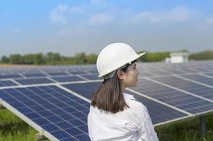 Ingenieurin mit Helm auf dem Feld der Photovoltaikzellen oder Sonnenkollektoren, umweltfreundliche und saubere Energie. foto