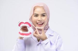 muslimische zahnärztin, die invisalign-klammern über weißem hintergrund hält studio, zahnpflege und kieferorthopädisches konzept. foto