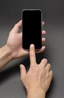 Schließen Sie herauf die Hand, die intelligentes Telefon über schwarzem Hintergrundstudio hält foto