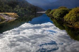 wolken spiegeln sich in einem fluss in neuseeland wider foto