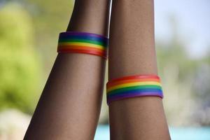 regenbogengummiarmbänder in den handgelenken asiatischer jungenpaare mit verschwommenem hintergrund, konzept zur feier der lgbt-gemeinschaft im stolzmonat oder im juni auf der ganzen welt. foto