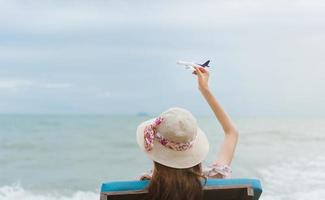 asiatische reisende frau hält flugzeugmodell in den himmel foto