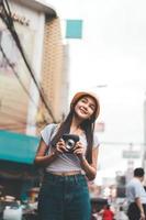junge asiatische reisende frau mit sofortbildkamera in bangkok, thailand foto