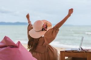 frau entspannen sich vom laptop, der in den ferien am strand arbeitet foto