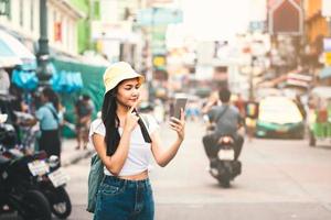 asiatische frau, die smartphone an der khaosan road verwendet foto