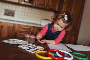 süßes kleines mädchen, entzückende vorschulkindmalerei mit aquarellen foto